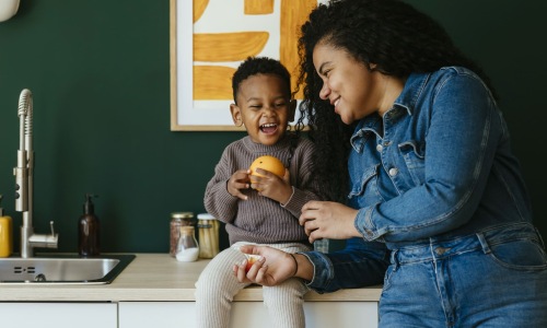 a woman and a child laugh in a kitchen area